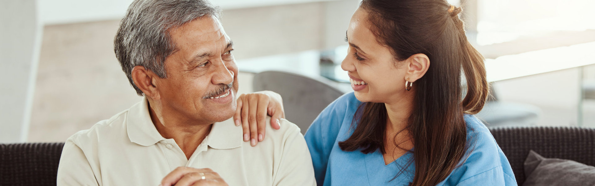 elderly man and caregiver smiling at each other